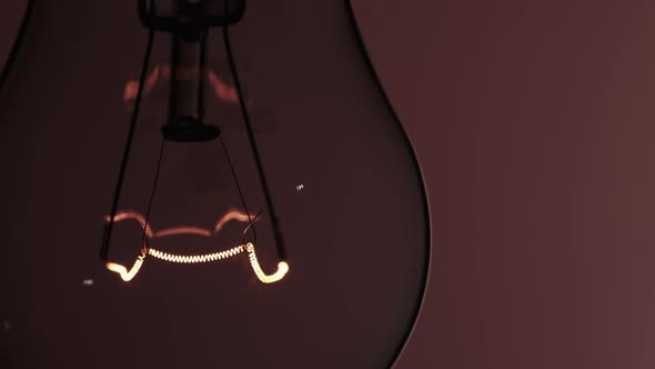 The Tungsten Filament in a Glass Lamp Closeup in Slow Motion on Red Background