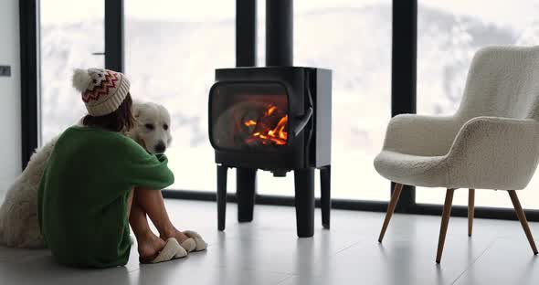 Woman with Dog at Home with Burning Fireplace During Wintertime