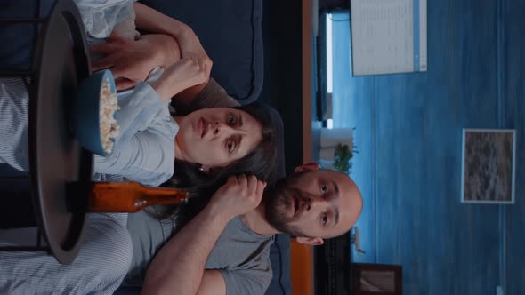 Vertical Video Shocked Scared Young Couple Eating Popcorn Watching Horror Movie on Tv