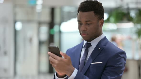 Attractive African Businessman Using Smartphone in Office