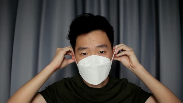 A Young Asian Man Wearing Medical Mask And Putting Off Mask