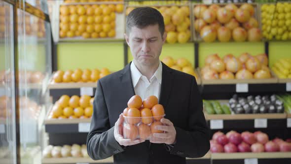 Portrait of Happy Male Grocery Customer Smelling Fresh Delicious Tangerines and Smiling at Camera