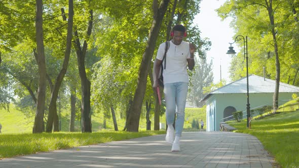 Wide Shot of Joyful African American Man Dancing To Music in Headphones As Walking Along the Alley