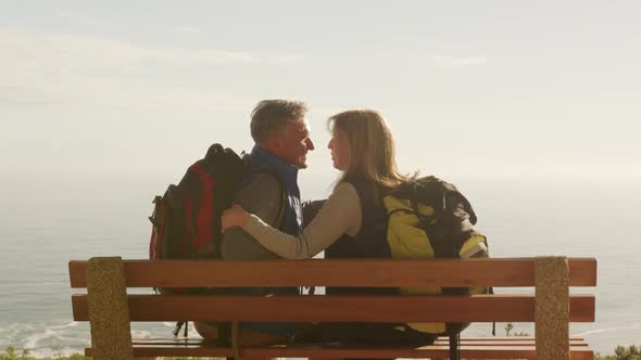 Active senior couple sitting on bench in forest