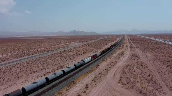 A freight train moves across the desert from a high angle.