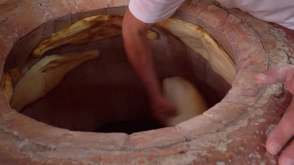 Baker making Turkish lavash in tandoor, clay oven. Baking process.