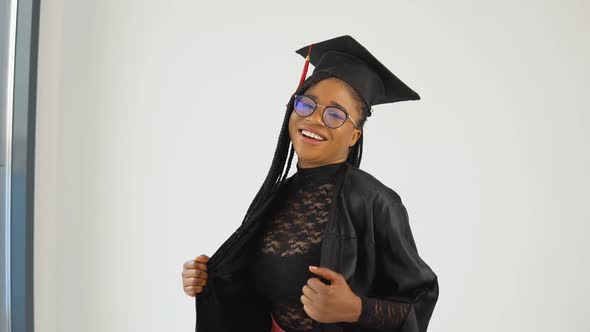 Happy Sexy Stylish Afro American Woman Student in Graduate Uniform Standing and Flirting on a White