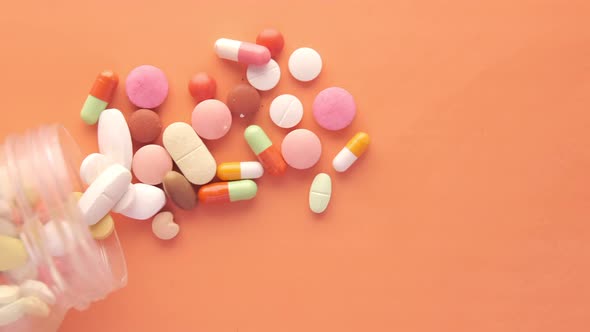 Close Up of Many Colorful Pills and Capsules on Orange Background