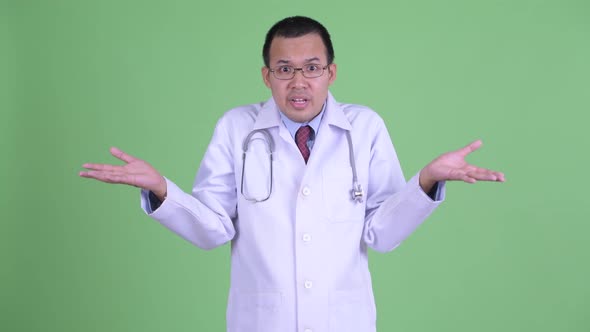 Confused Asian Man Doctor with Eyeglasses Shrugging Shoulders