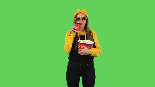 Modern Girl in Yellow Hat in 3D Glasses Is Watching a Movie, Eating Popcorn and Drinking Coffee