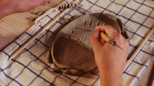 Pottery in the Studio  Woman Makes Patterns on a Piece of Clay