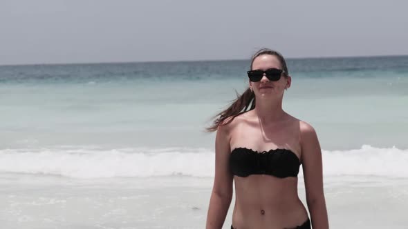 Young Woman in a Black Swimsuit Walks From the Turquoise Ocean on Paradise Beach