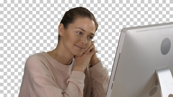 Blonde girl with pink pullover looking at monitor of computer