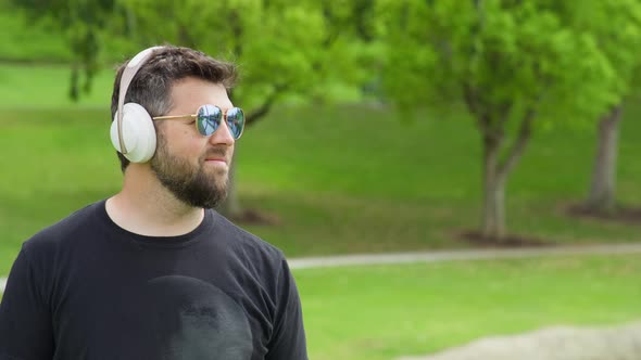 Smiling Bearded Man Listening Music Through the Wireless Headphones