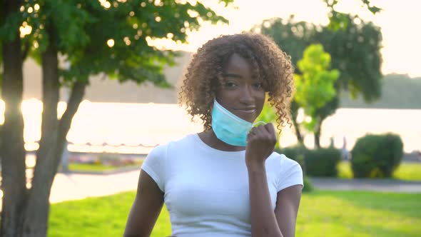 African American Girl Removes a Medical Mask at Park