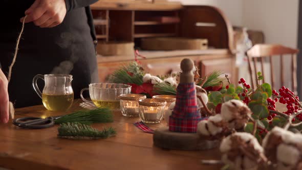 Crop woman making Christmas decorations at table