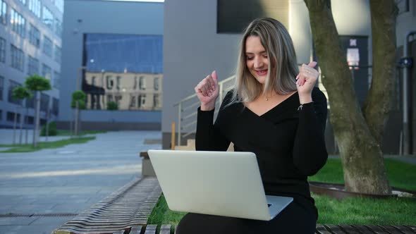 Attentive Woman Working on a Laptop Sitting Bench in the Street