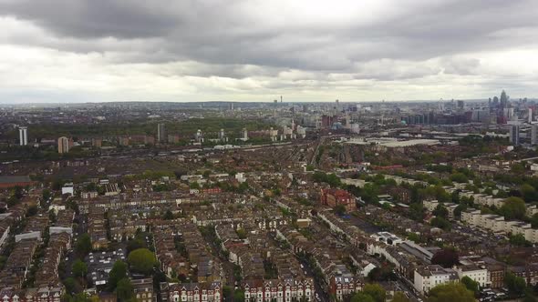 Flying above streets of terraced houses with train lines and City skyline in the background