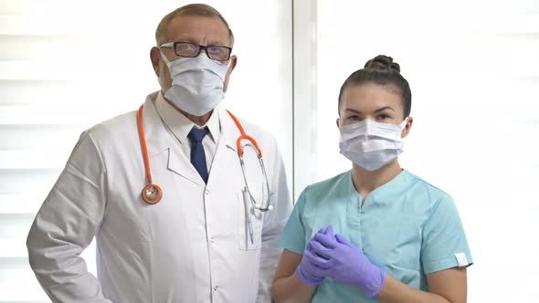 Portrait of an Elderly Male Doctor and a Young Nurse Wearing Medical Masks. Professional Tandem