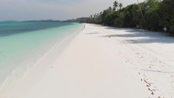 Aerial: Woman relaxing on white sand beach turquoise water tropical coastline