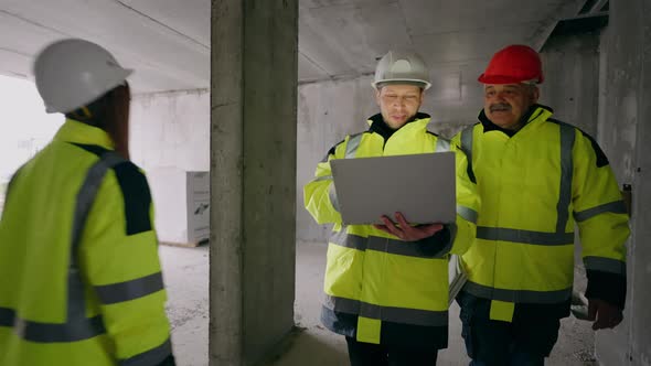 Civil Engineers are Viewing Construction Plan in Laptop and Examining Underconstruction Building