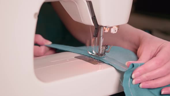 Close-up of a seamstress stitching fabric on a sewing machine. Tailoring at home.