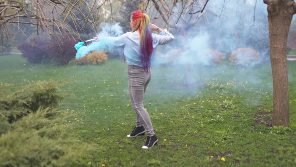 Beautiful Girl in with Multicolored African Braids Posing with Blue Smoke Against the Background of