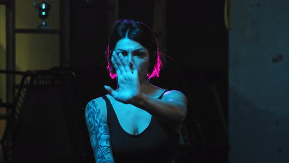 A Strong Tattooed Woman Showing Karate Moves in Neon Lighting