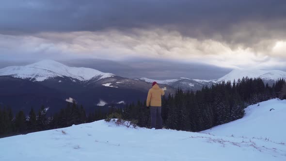 A Traveler Talks on the Phone in the Mountains in Winter