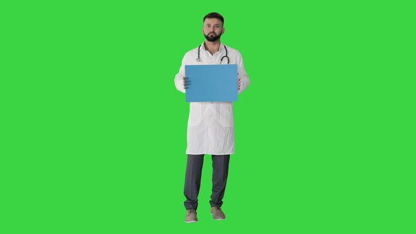 Arab Doctor Standing Showing Placard and Telling Something on a Green Screen, Chroma Key.