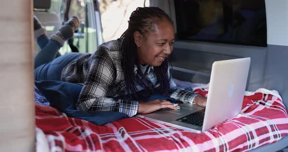 Mature african woman using computer laptop inside mini van camper