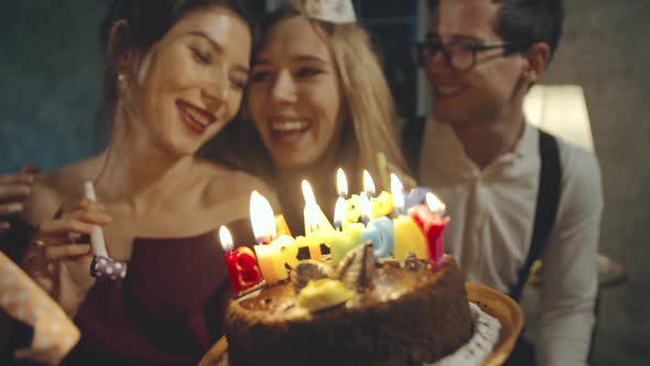 Portrait of Asian Girl Wearing Birthday or Party Cap Blowing Whistle and Holding Birthday Cake with