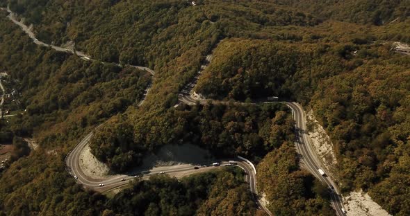 Aerial View of Car Driving Along The Winding Mountain Pass Road Through The Forest Trees. Autumn