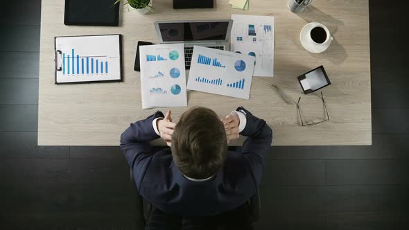 Tired Businessman Sitting at Table in Office, Thinking About Project, Top View