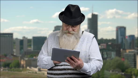 Old Man in Hat Using Digital Tablet Outdoor