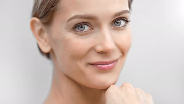 Beautiful Female Face with First Wrinkles Smiling Looking at Camera Isolated at Light Background