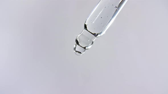 Cosmetic Pipette with Drops of Oil Close Up on Gray Background