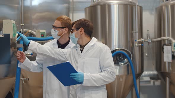 Men with Clipboard Wearing Lab Coat and Protective Mask Working at Craft Brewery