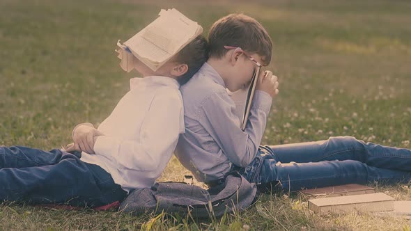 Exhausted Young Schoolmates Sleep with Books on Face