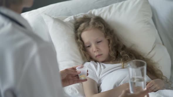 Nurse Offering Pills to Unhappy Child With Low Immune System, Flu Epidemic