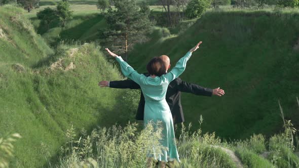 Back View Slim Woman in Elegant Dress Stretching Hands with Man in Suit Looking Away