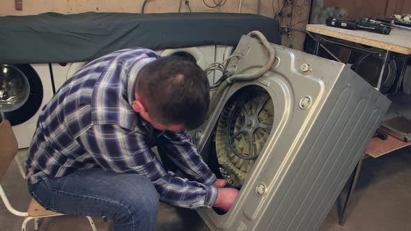 The Technician Installs a New Part in the Washing Machine