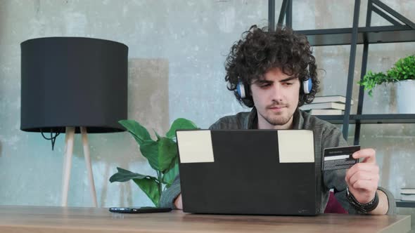 Young Man Shopping Online with Credit Card Using Smart Phone at Home