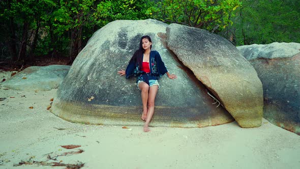 Cute Smiling Asian Girl Sitting on a Rock on a Beach in Slow Motion Thailand