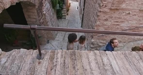 Four Happy Tourist People Walking and Running Through Small Street Visiting Rural Town of Spello