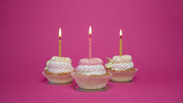 birthday cupcake with candles and birthday decorations on pink background