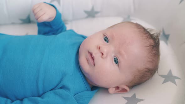Cute Newborn Kid in Bodysuit Looks at Camera in Cocoon