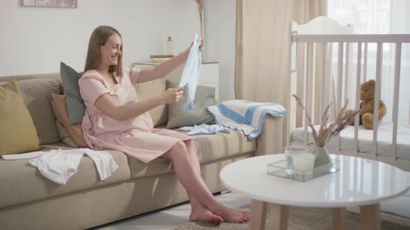 Expectant Woman Preparing Newborn Boy Clothes