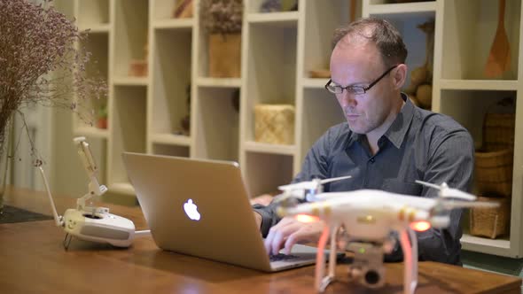 Mature Man with Drone and Laptop in the Dining Room at Home