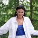 Attractive Woman in White Jacket and Blue Top Posing Against the Background of Green Trees - VideoHive Item for Sale